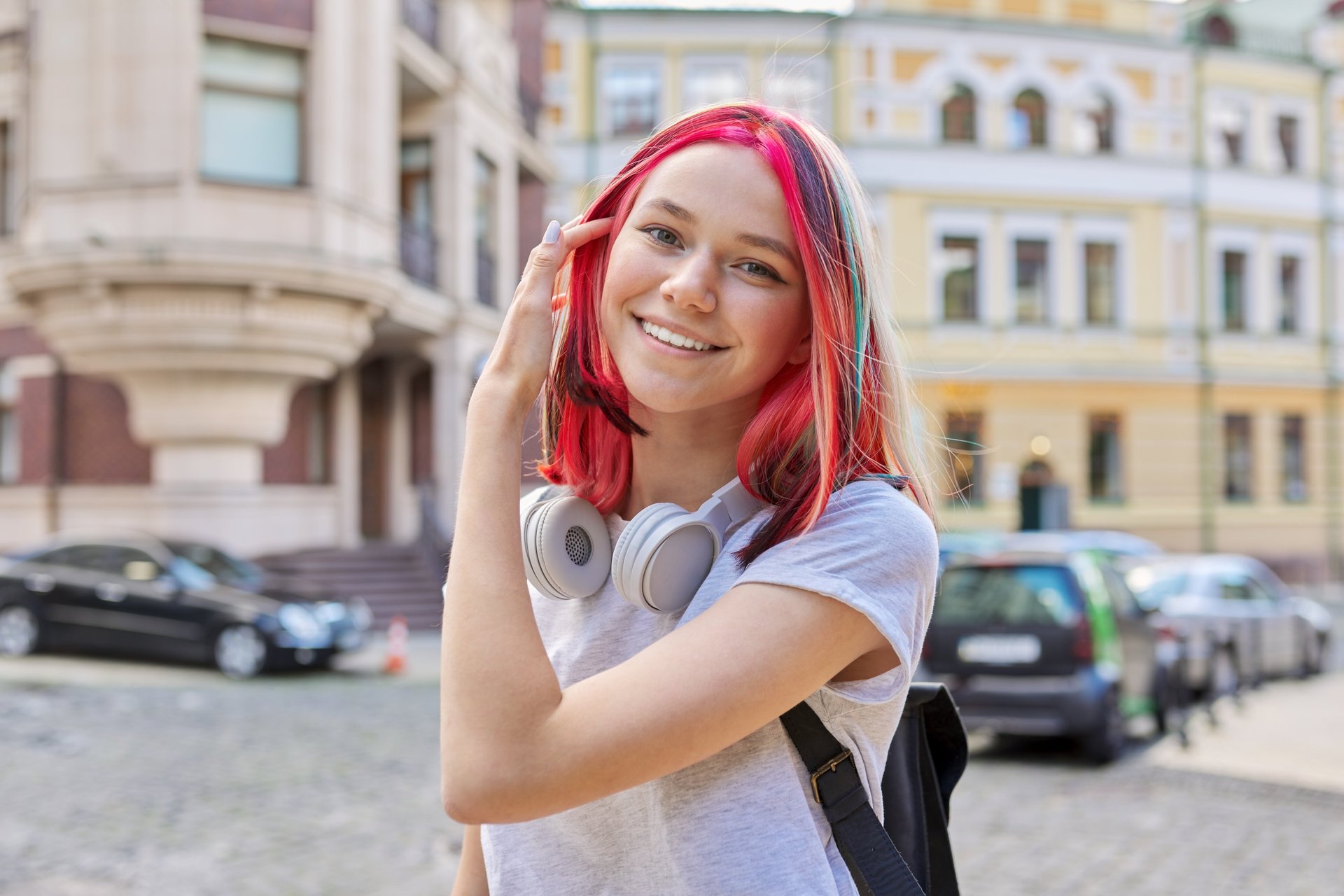 Eine Jugendliche steckt sich die Haare hinter die Ohren und lächelt in die Kamera.