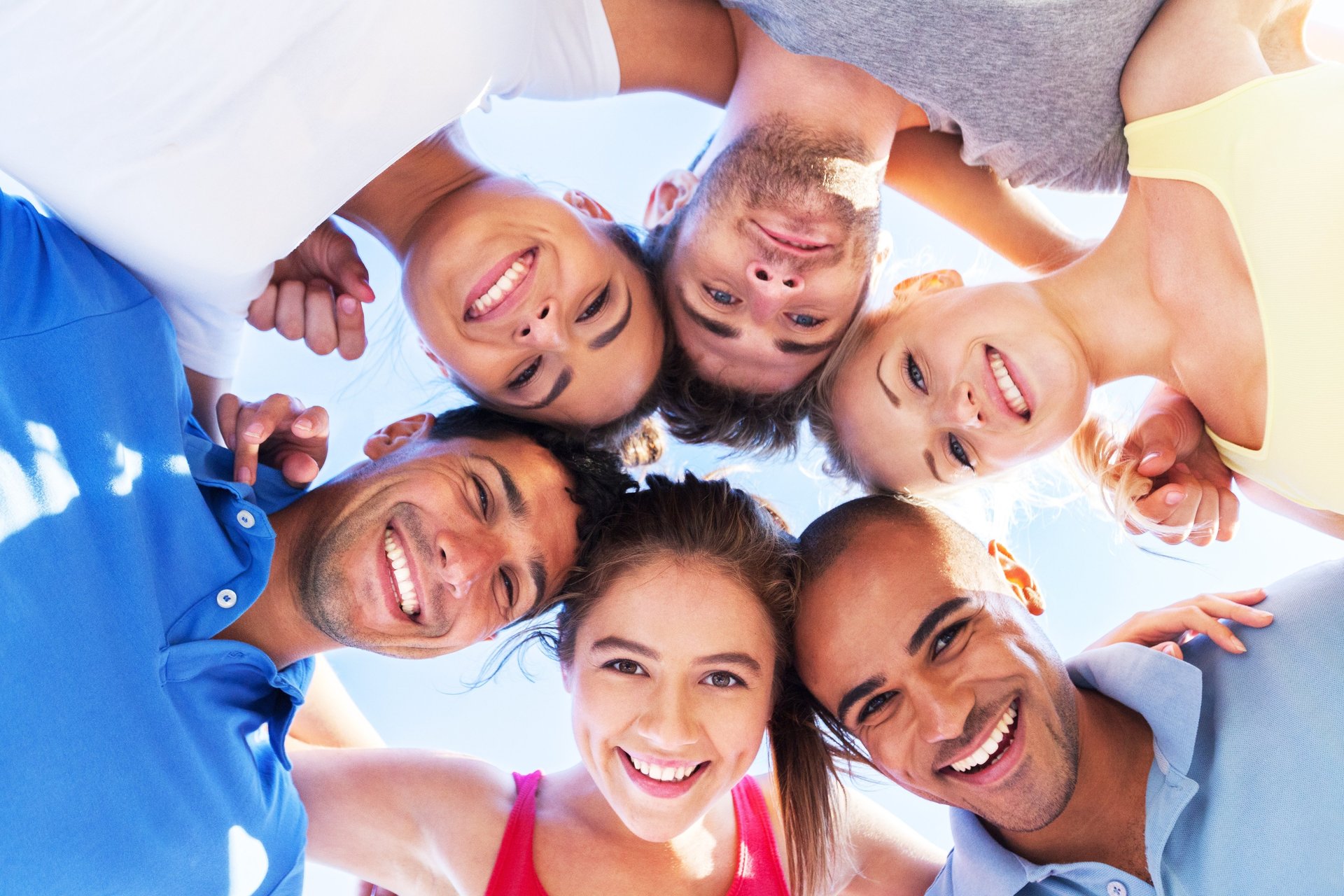 Eine Gruppe Menschen steht in einem Kreis und beugt sich über eine Kamera.