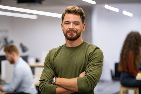 Ein Mann steht mit verschränkten Armen in einem Büro.