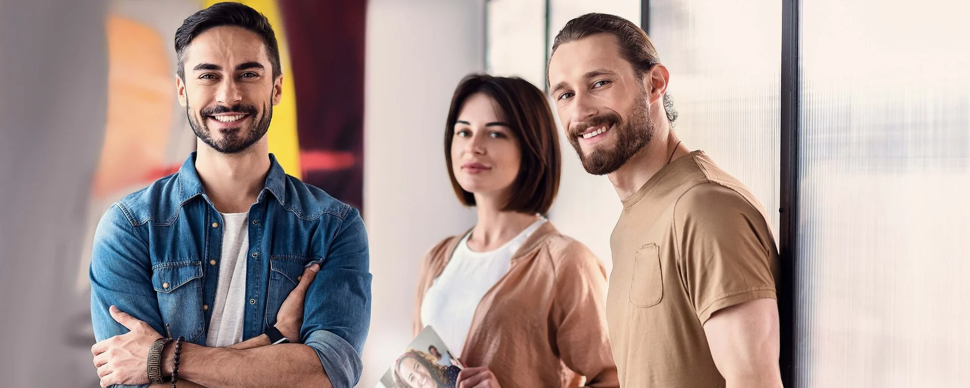 Eine Gruppe von Mitarbeiter*innen steht in einem Büro und hält eine DAA-Broschüre in der Hand.