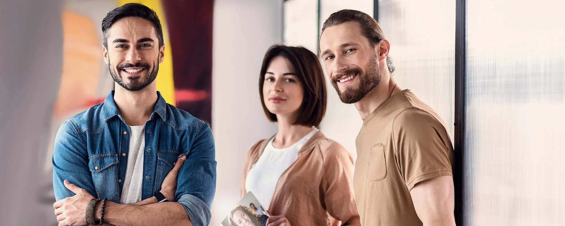 Zwei Männer und eine Frau mit einer DAA-Broschüre in der Hand  stehen in einem Flur
