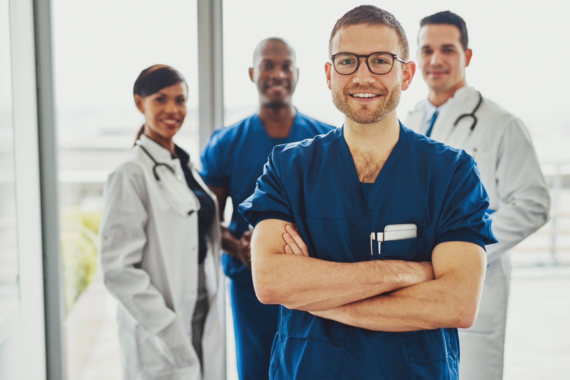 Ein Pflegefachmann steht vor einer Gruppe Kolleg*innen in einem Krankenhaus.