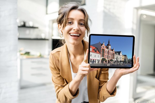 Eine Frau hält ein Tablet mit einem Bild der Stadt Strausberg in der Hand.