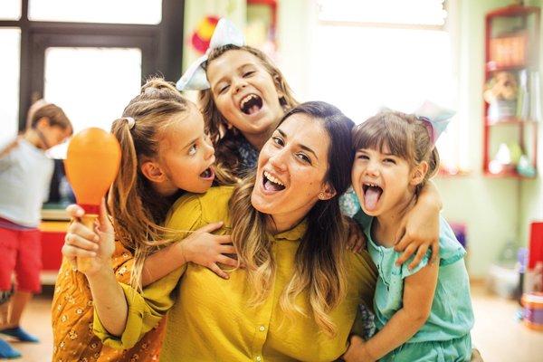 Eine Erzieherin spielt mit Kindern in einem Kindergarten.