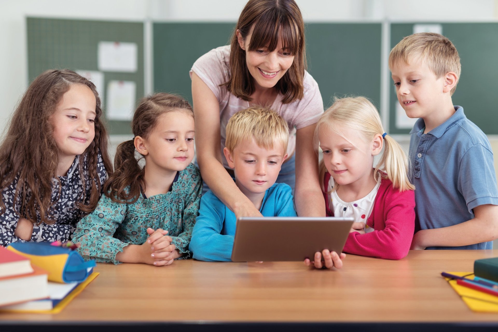 Eine Erzieherin zeigt Kindern etwas an einem Laptop.