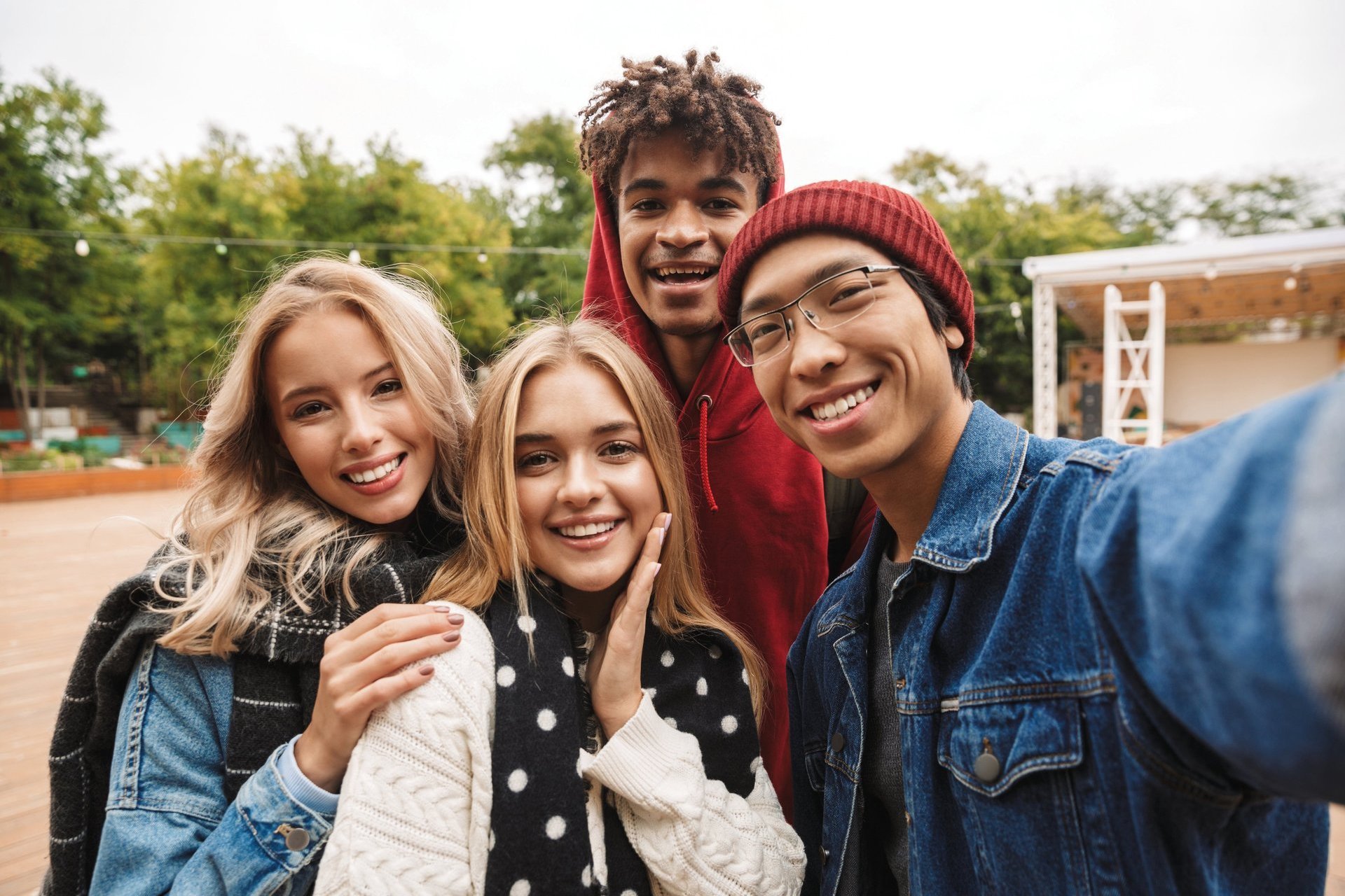 Eien integrative Gruppe Jugendlicher steht in einem Park und lächelt in die Kamera.