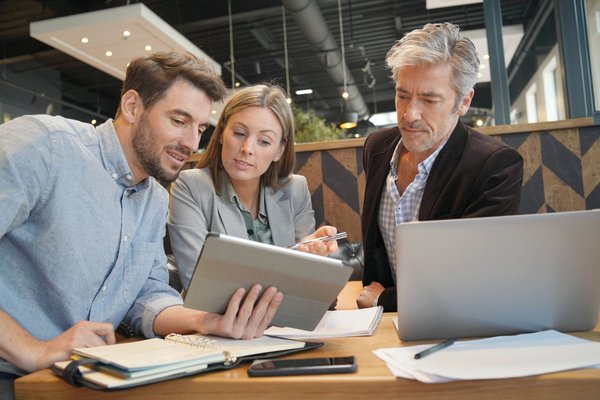 Drei Existenzgründer*innen sitzen gemeinsam an einem Business-Plan.