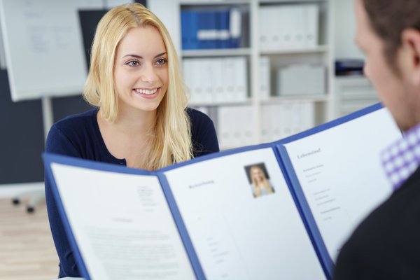 EIne Frau sitzt ihrem Bewerbungscoach gegenüber und lächelt.