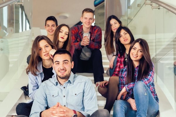 Eine integrative Gruppe Jugendlicher sitzt auf einer Treppe in einer Schule.