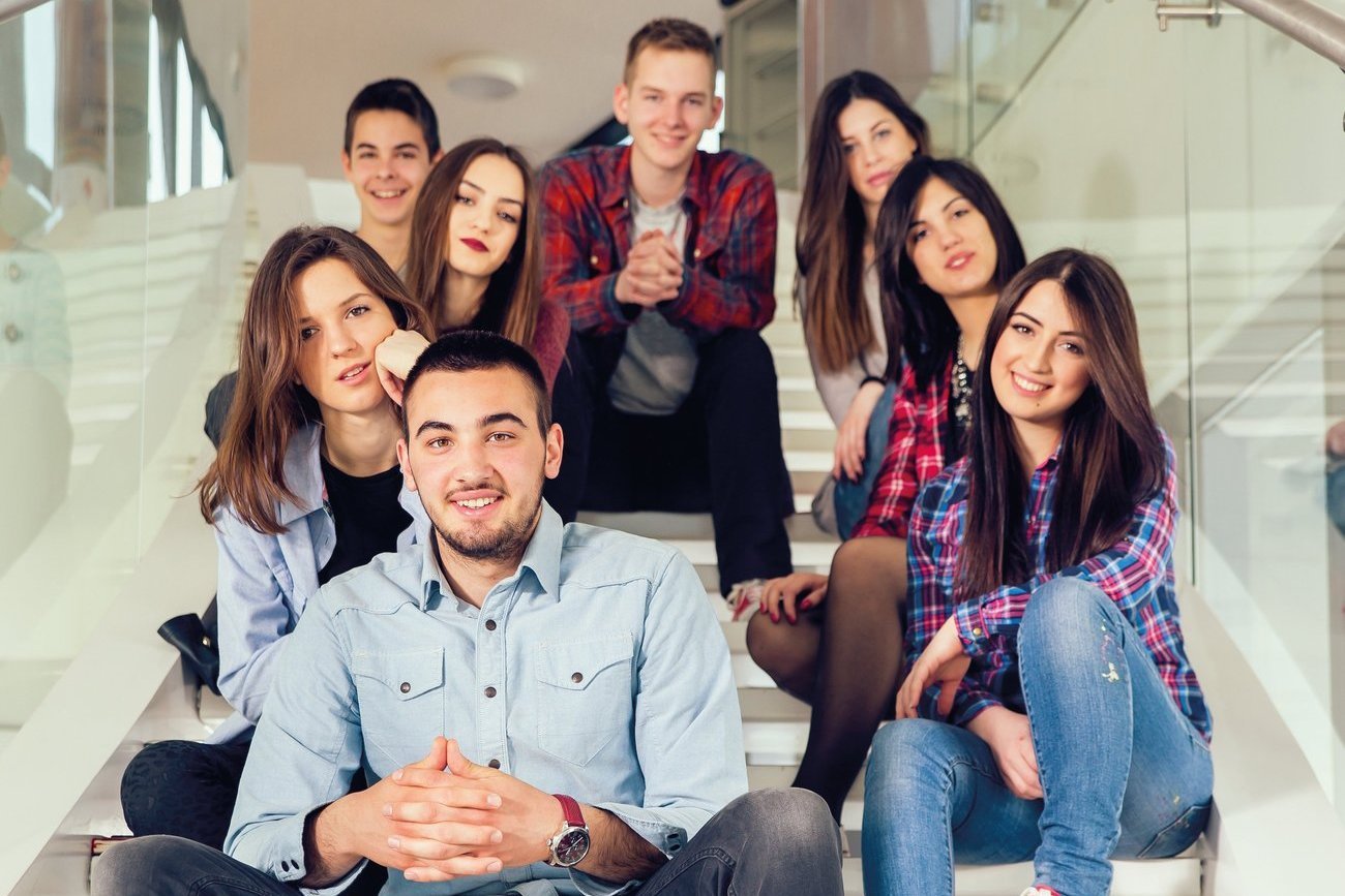 Eine integrative Gruppe Auszubildender sitzt auf einer Treppe.