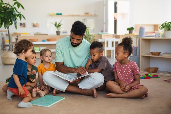 Ein Erzieher liest mit einigen Kindern ein Buch.