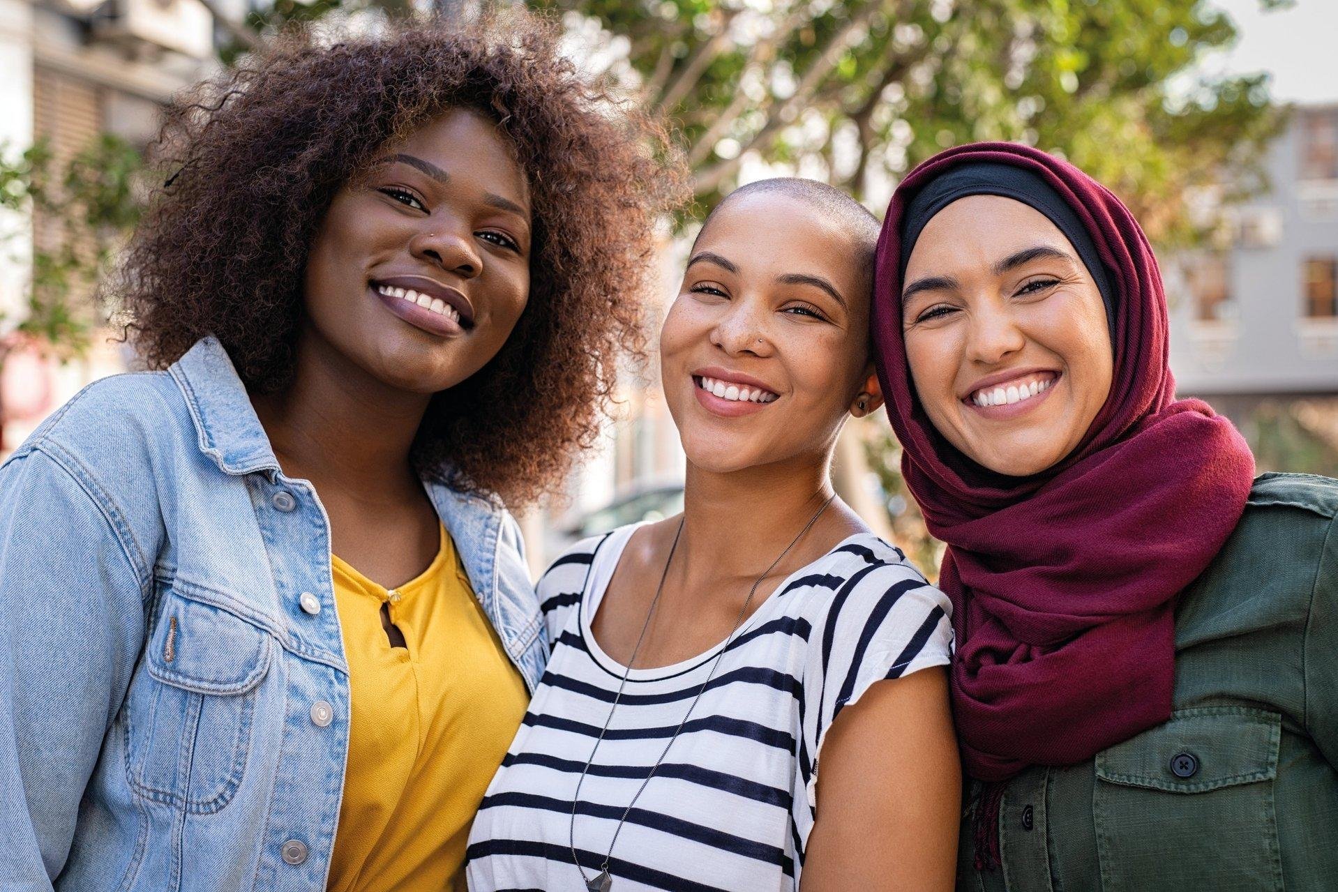 Drei junge Frauen aus einem Integrationskurs lächeln in die Kamera.