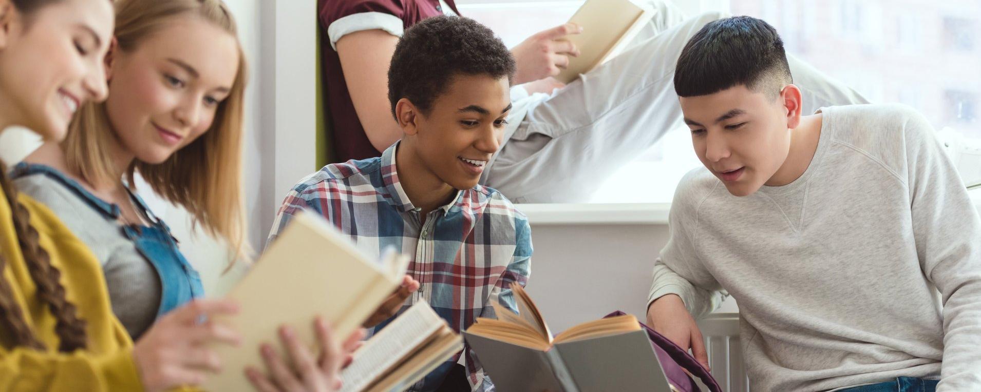 Gruppe Jugendlicher schaut gemeinsam in ein Buch