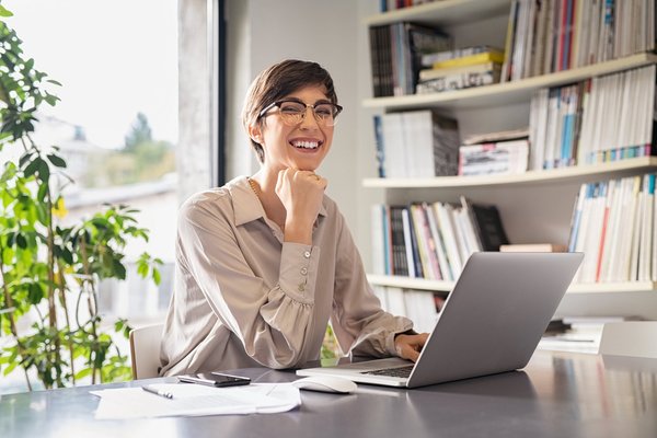 Eine Frau sitzt in einem Büro an einem Lapotop und arbeitet.