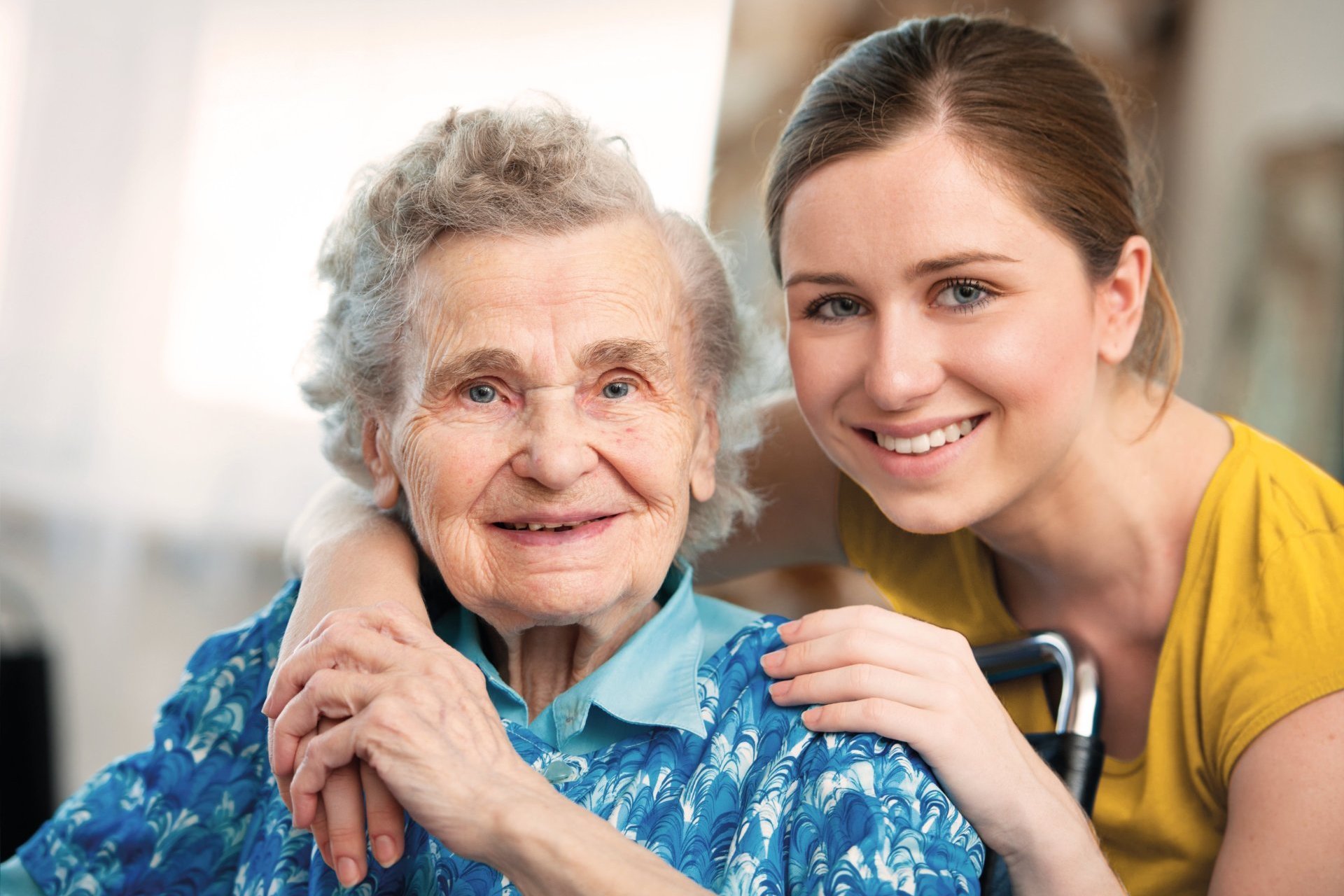 Eine junge Pföegerin hält eine Patientin im Arm.