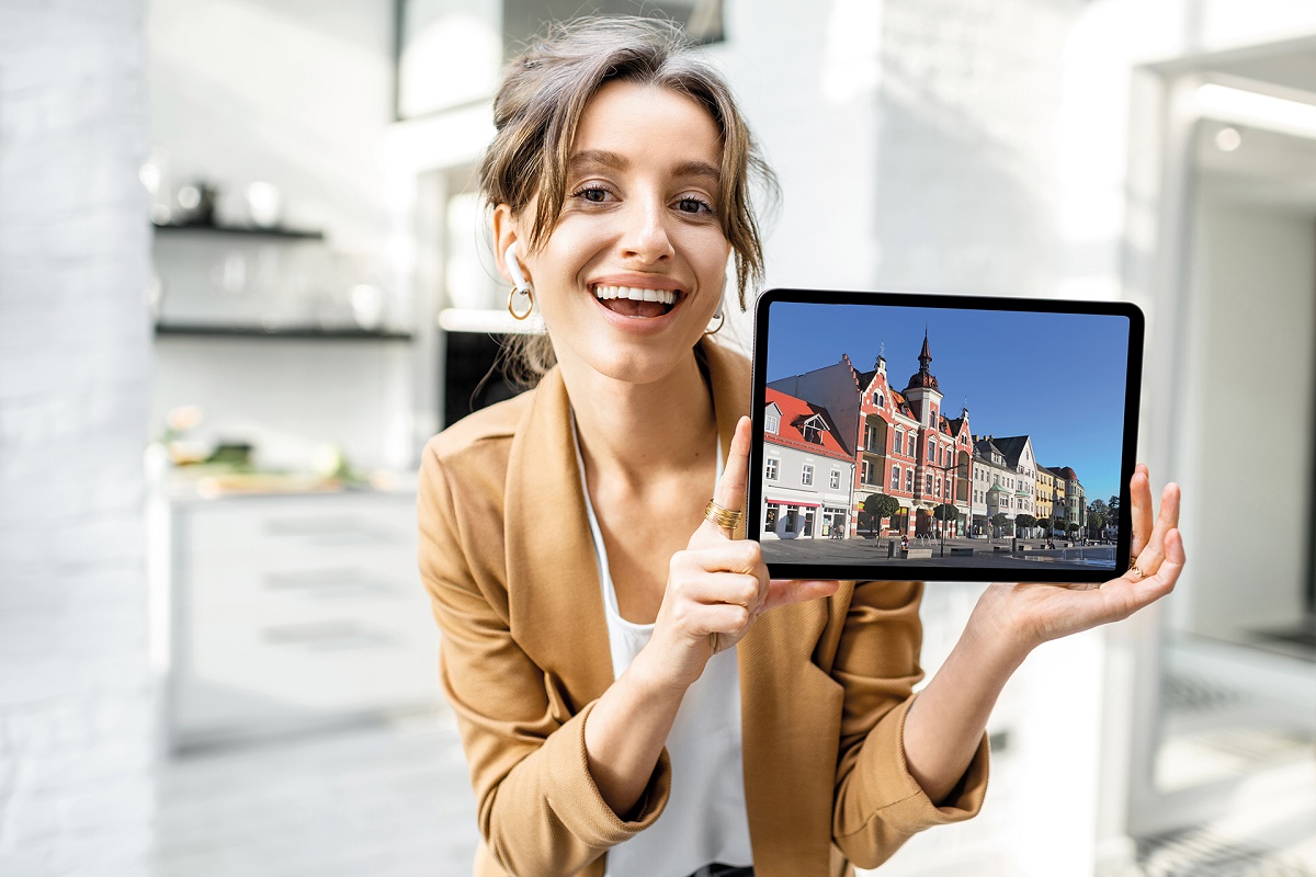 EIne Frau hält ein Tablet mit einem Foto der Stadt Finsterwalde in der Hand.